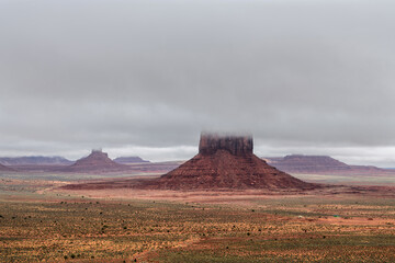 Monument Valley Buttes covered with low rain clouds during a gloomy day in the desert.