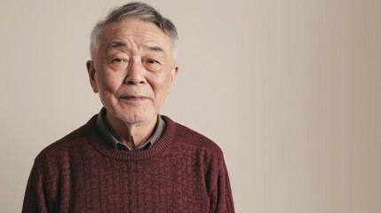 portrait of Asian elderly man is 65 years old in deep marsala color sweater on beige color background, closeup