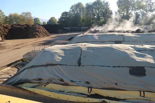 Composting windrows covered with semipermeable membrane to protect them from weather conditions.