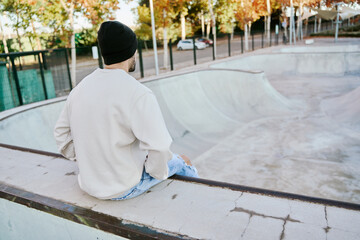 young skateboarder sitting on the kerb of an empty skatepark. - Powered by Adobe