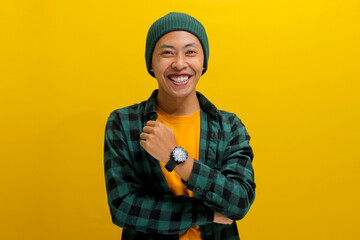 Confident young Asian man, clad in a beanie hat and casual outfit, stands with folded arms, wearing...