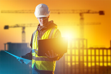 Man architect. Builder guy against background of sunset. Architect engineer stands with laptop in...