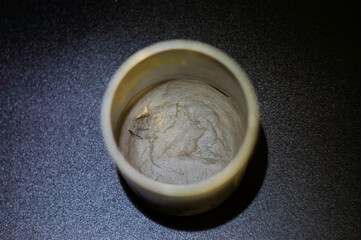 half empty gray paste in gray container on black background highlighted