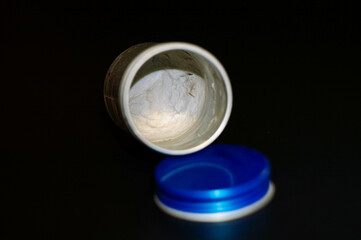 empty gray paste in gray container with blue closure on black background highlighted