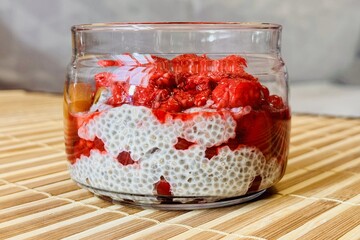 Healthy Chia pudding with coconut milk in glass container in view can with fresh berries as...