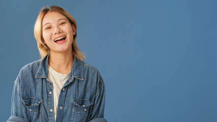 Happy young woman dressed in denim shirt looks at the camera and laughs, mockup space, isolated on...