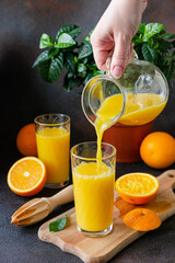 Orange juice is poured into a glass. Orange juice in a glass on a dark background