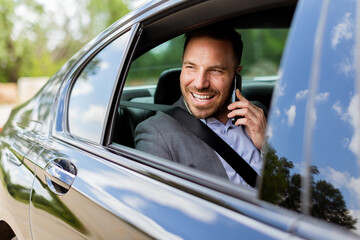 Joyful man sharing laughter on a phone call while driving in daylight