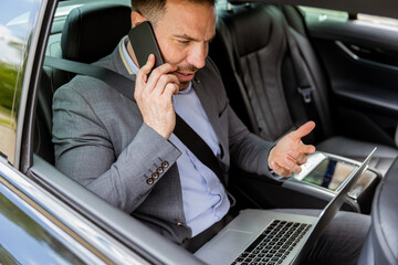 Busy executive managing time effectively while multitasking in his vehicle