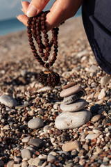 a girl on the background of the sea is holding a rudraksha necklace