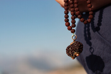 a girl on the background of the sea is holding a rudraksha necklace