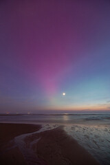 Moon with purple colored northern lights (Aurora borealis) over the North Sea