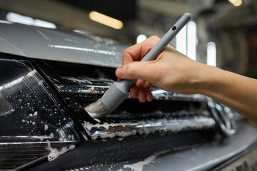 A person is cleaning a car windshield with a brush and water
