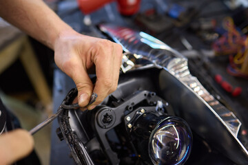 Person fixing Automotive lighting with screwdriver on Motor vehicle headlight