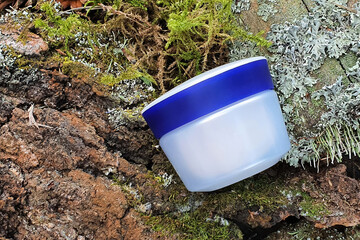 Cosmetic moisturizer cream jar with blue screw cap and green forest moss.Cosmetic bottle container...