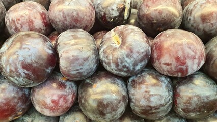 Close up pile of tasty fresh plums sold at the market as a background.