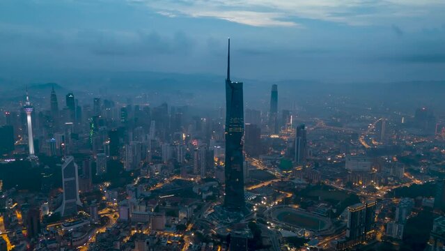 Aerial view time lapse 4k video of Kuala Lumpur city center view at sunrise dawn overlooking the city skyline in Federal Territory, Malaysia during low clouds sunrise. 