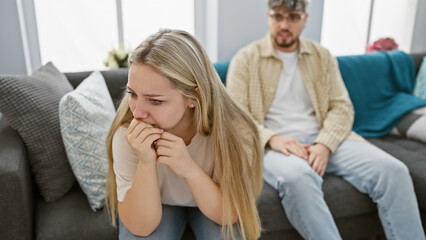 A worried woman and a blurry man sitting in a modern living room, portraying relationship concerns...