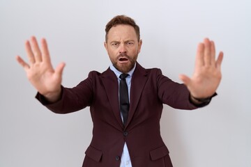Middle age business man with beard wearing suit and tie doing stop gesture with hands palms, angry...
