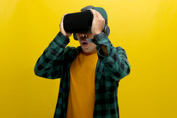 Amazed Asian man wearing a VR headset watches a captivating 3D experience. Isolated on a yellow background.