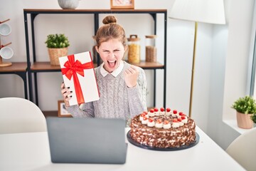 Young blonde woman goes ballistic at home, yelling at laptop, frustration boiling over while...