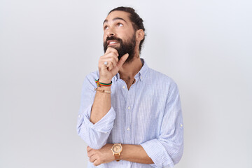 Hispanic man with beard wearing casual shirt with hand on chin thinking about question, pensive...