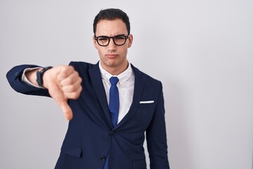 Young hispanic man wearing suit and tie looking unhappy and angry showing rejection and negative...