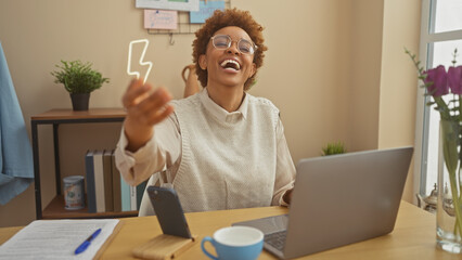 A joyful african american woman in a sweater reaches out at home with a laptop and coffee on her...