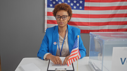 African american woman at a polling station with a ballot box and american flag during election in...