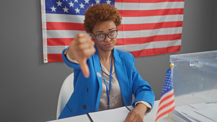 African american woman giving thumbs down in a voting center with us flag.