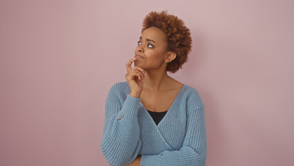 A contemplative african american woman poses against a plain pink background, exuding beauty and...