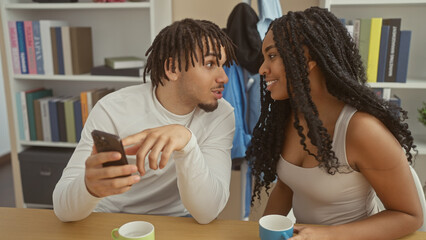 Man and woman engaging with smartphone in a cozy home setting, reflecting a modern couple's indoor...