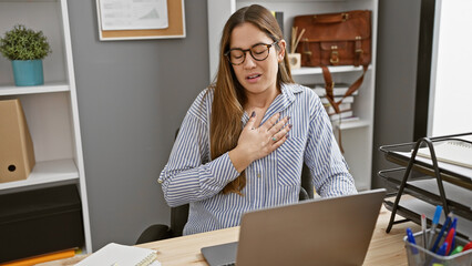 A young woman experiences chest pain while working at her office, indicating potential health...