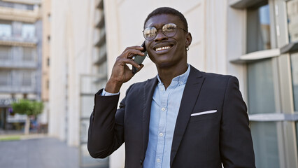 Handsome african man in suit using smartphone on sunny city street