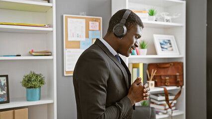 African american businessman with headphones enjoying music in a modern office setting.
