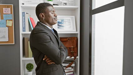 Confident african american man with arms crossed standing in a modern office setting.