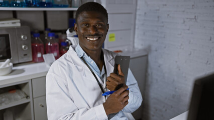 African man in lab coat smiling in laboratory with clipboard and pen, portraying a professional...