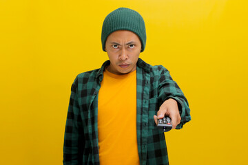 An irritated young Asian man, dressed in a beanie hat and casual shirt, switches TV channels,...