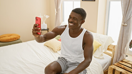 Handsome black man taking a selfie in a bright bedroom