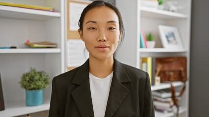 Portrait of a composed young asian woman in an office setting, evoking professionalism and...