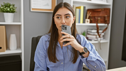 Hispanic woman with smartphone in modern office.