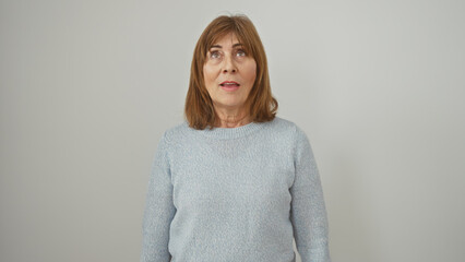 Mature woman with short hair looks upwards against a white isolated background, expressing...