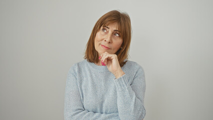 Mature woman in thoughtful pose against a white background wearing a blue sweater.