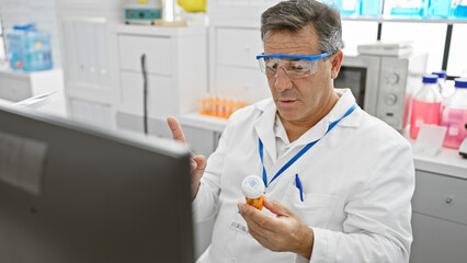 Mature man in lab coat examines medicine bottle in brightly-lit hospital laboratory