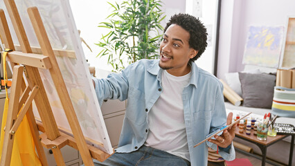Handsome man painting on canvas in a bright indoor studio setting