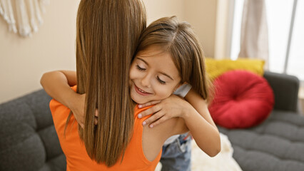A smiling girl embraces her mother in a cozy living room, reflecting family, love, and a happy home atmosphere.