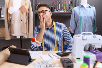 Hispanic man with beard dressmaker designer working at atelier bored yawning tired covering mouth...
