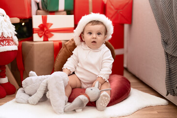 Fototapeta premium Adorable toddler sitting on floor by christmas gift at home