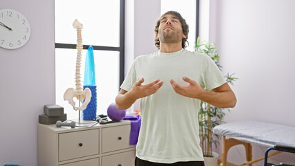 Handsome young man with beard doing breathing exercises in a bright rehabilitation clinic room