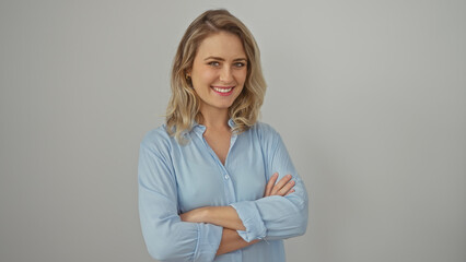 Confident young blonde woman in casual clothing, posing with arms crossed against a clean white background.